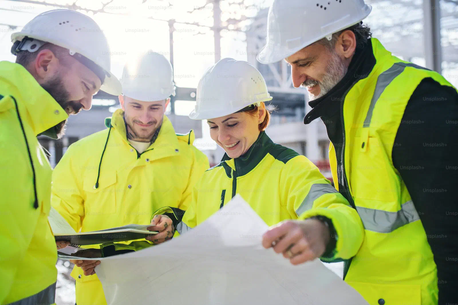 Ingenieure mit Schutzhelmen prüfen Baupläne auf Baustelle, Fachbauleitung GA/TGA WENGET